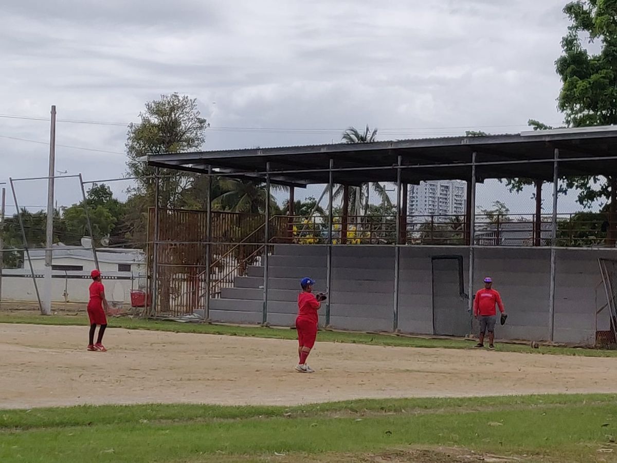 Three players in red uniforms on a baseball field in Puerto Rico