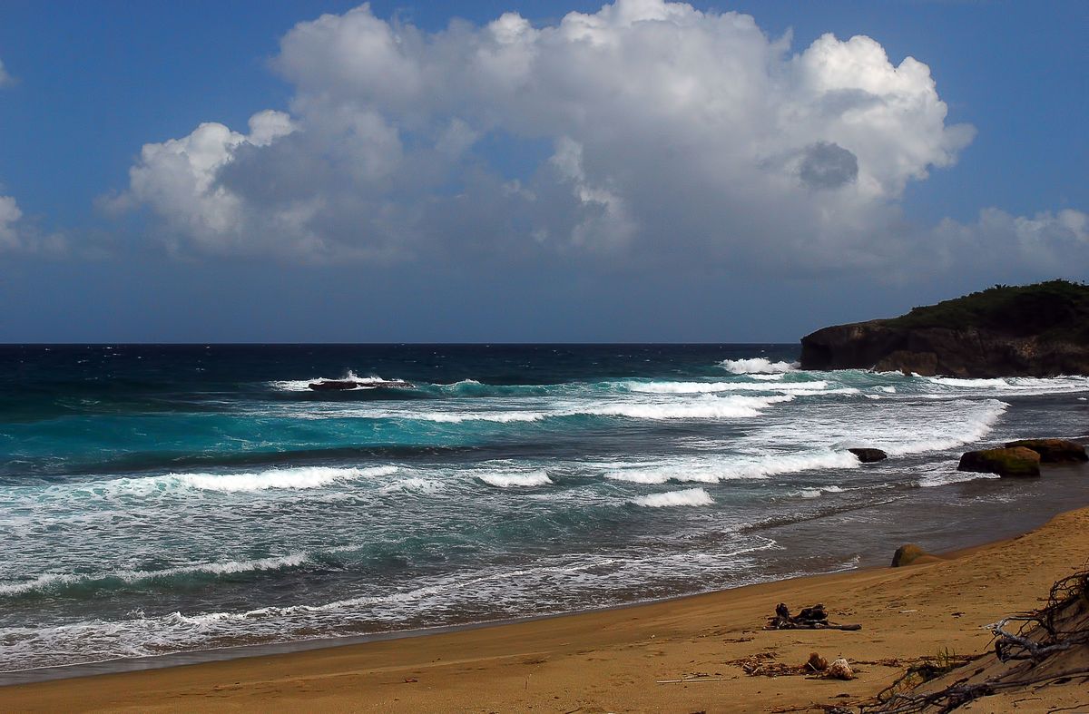 Jobos Beach in Isabela, Puerto Rico, with waves breaking near a rocky cliff