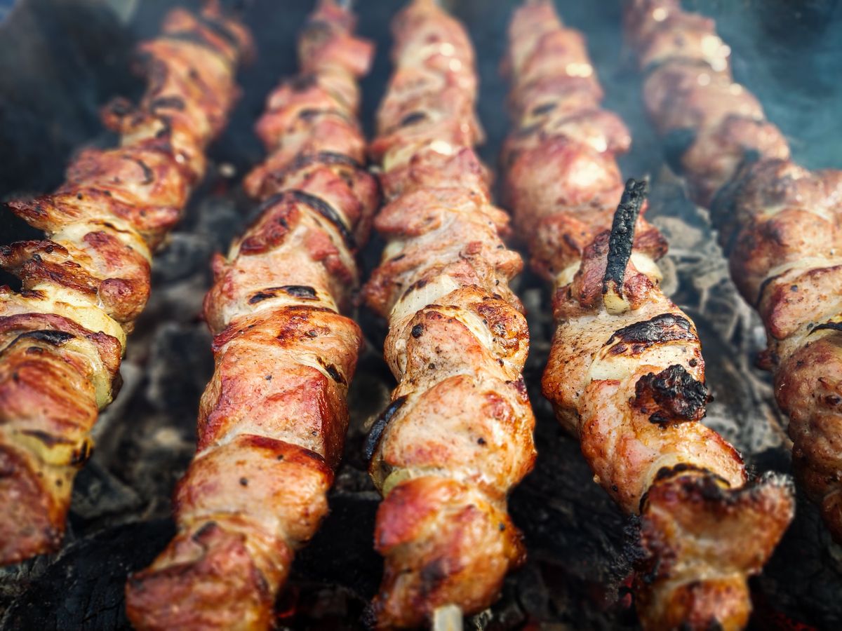 Skewers of grilled pork pinchos cooking over hot charcoal