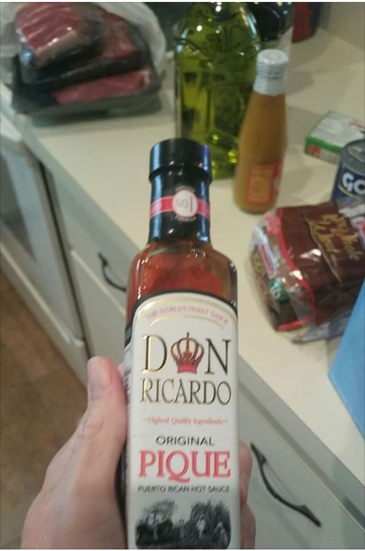 A hand holding a bottle of Puerto Rican pique hot sauce, labeled Original Pique